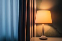 Elegant table lamp with warm glow beside window with blue and brown curtains, creating cozy ambiance for home interior design.