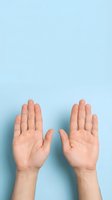 Two open hands with palms facing up on light blue background showing gesture of receiving, giving or presenting with copy space above.