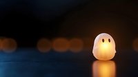 Glowing white ghost lamp with yellow eyes creating warm ambient lighting on dark surface with soft bokeh background for Halloween decoration.