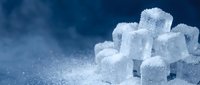 White sugar cubes stacked on blue surface with granulated sugar, suitable for food and beverage advertising, culinary content, and nutrition-related designs.