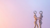 Two metallic wire figures dancing together on soft pink purple gradient background for romantic celebration concepts.
