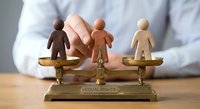 Business professional balancing diverse wooden figures on golden equal rights scale representing workplace equality and fair treatment concepts.