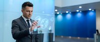 Professional businessman in suit interacting with holographic global network interface in modern office environment for technology presentations.