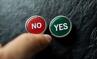 Finger pointing at red no and green yes buttons on dark textured background, representing choice, decision making and options in business and life.