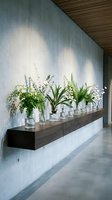Modern minimalist interior with floating wooden console displaying glass vases filled with fresh green plants against concrete wall in contemporary home.