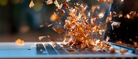 Dramatic copper metal shavings exploding and flying off laptop keyboard in macro photography with motion blur effect and dark background.