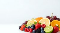 Fresh mixed fruits and berries arrangement with citrus slices on white background for healthy eating and nutrition concepts.