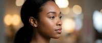 Professional African American businesswoman in modern office environment with warm bokeh lighting background for corporate presentations.