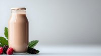 Fresh chocolate milk or protein shake in glass bottle with raspberries and blackberries on light background, healthy breakfast beverage concept.