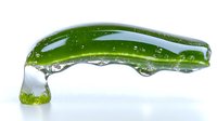 Fresh green cucumber slice with water droplets suspended underneath on white background, macro photography showing transparency and liquid dynamics.