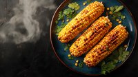 Grilled corn on blue ceramic plate with fresh herbs and spices, steam rising against dark background. Rustic food photography for restaurant menu.