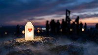 White lantern with red heart symbol glowing on misty rock at dusk, city skyline silhouetted in background, conveying hope and love for greeting cards and inspirational designs.