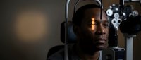 African American man having comprehensive eye examination using modern optometry equipment at ophthalmologist office for vision health checkup.