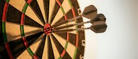 Three darts hitting bullseye center of dartboard showing precision accuracy and target achievement in competitive sport game.
