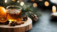 Hot mulled wine with orange, cinnamon sticks and star anise on wooden board. Pine cones and Christmas tree branches create cozy winter atmosphere with bokeh lights.