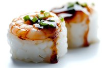 Fresh sushi rolls with cooked shrimp, white rice, teriyaki sauce and green onion garnish on bright background, macro food photography with selective focus.