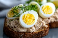 Open sandwich with liver pate and boiled eggs garnished with fresh dill on dark bread for healthy breakfast or lunch meal preparation.