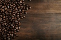 Roasted coffee beans scattered on dark wooden background, creating contrast between rich brown beans and rustic wood texture.