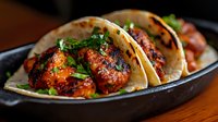 Grilled spicy meatballs in soft tortillas with fresh herbs served on cast iron skillet for Mexican cuisine restaurant menu and cooking blog content.