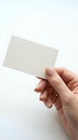 Female hand holding blank white business card mockup on clean background for branding and corporate identity design projects.