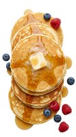 Stack of golden pancakes topped with melting butter and fresh blueberries and raspberries, isolated on white background for breakfast menu design and food advertising.