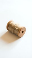 Wooden spool with natural jute twine thread isolated on white background for crafting and sewing projects.