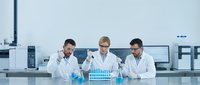 Three male scientists in white lab coats conducting research with test tubes in modern laboratory setting for medical and scientific applications.