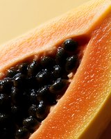 Fresh ripe papaya slice showing juicy orange flesh and black seeds in macro close-up, highlighting natural texture and vibrant tropical fruit details.