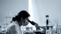 Female scientist examining samples through microscope in modern laboratory conducting medical research and analysis.