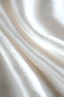 Elegant white silk fabric with soft folds and delicate texture creates gentle waves and shadows, suitable for wedding, fashion, and luxury design backgrounds.