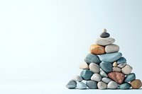 Balanced stack of smooth river stones forming pyramid shape on light background, zen meditation concept for spa and wellness centers.