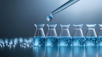 Laboratory glass vials with blue liquid and pipette dropping sample for medical research, pharmaceutical testing and scientific experiment analysis.