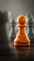 Wooden pawn chess piece in sharp focus with blurred chess pieces in background, symbolizing leadership, strategy, and business advancement on wooden board.