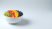 Fresh mixed fruit salad with kiwi, strawberry, orange, and blueberry in white bowl on white background, healthy eating and nutrition concept.