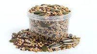 Mixed seeds and nuts in glass jar isolated on white background for healthy snacking and cooking ingredients.