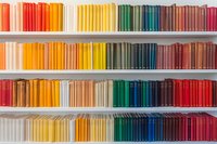 Colorful books arranged by spectrum colors on white shelves creating rainbow pattern, organized collection displaying vibrant spines from red to yellow to green and blue.