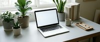 Laptop with blank screen on white desk surrounded by potted plants, books, and office supplies in bright workspace for business, technology, and productivity design projects.