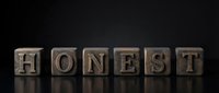 Wooden letter blocks spelling HONEST on dark surface representing integrity, trust, ethics and moral values in business communication.