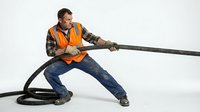 Construction worker in safety vest pulling heavy rope in tug of war position isolated on white background for teamwork and strength concepts.