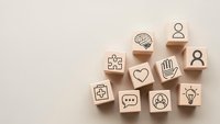 Wooden blocks with business and communication icons arranged on beige background for corporate branding and marketing materials.