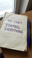 Open notebook with handwritten motivational message about letting go of control on wooden desk with blue pen for mindfulness and personal growth.