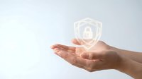 Hand holding glowing shield with padlock icon, representing data protection, cybersecurity, and digital safety solutions for business applications.