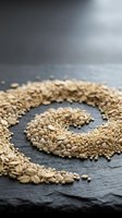 Sesame seeds arranged in spiral pattern on dark slate surface with soft studio lighting, suitable for food photography, culinary content, nutrition articles, and organic product marketing.