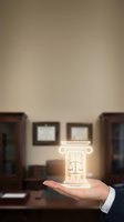Hand holding a glowing justice scales icon in a law office, symbolizing legal expertise, attorney services, and judicial balance.
