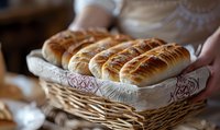 Fresh baked sausage rolls with golden flaky pastry arranged in wicker basket lined with white cloth, warm natural lighting creates appetizing mood.
