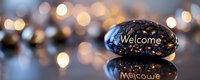 Decorative black stone with welcome message engraved against blurred golden bokeh lights background creating warm atmospheric mood for greeting cards and banners.