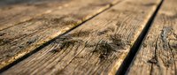 Weathered wooden planks with natural grain patterns and rustic texture for flooring, construction, and carpentry projects in warm natural lighting.