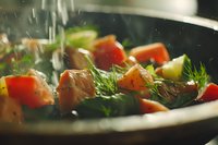 Fresh salmon pieces with dill and vegetables being cooked in pan with water droplets splashing, dramatic lighting creates appetizing mood for food photography.