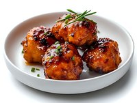Glazed Asian meatballs garnished with fresh chives served on white ceramic plate, featuring caramelized sauce with sweet and savory flavors for appetizer or main dish.