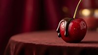 Fresh red cherry with dark chocolate dripping down on elegant burgundy velvet surface creating luxurious dessert presentation for gourmet food styling.